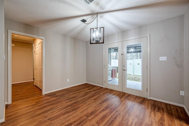 unfurnished dining area featuring a textured ceiling, french doors, dark wood-type flooring, and baseboards