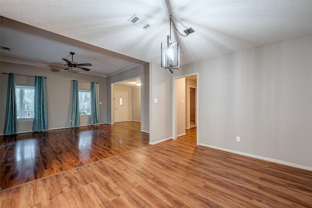 unfurnished living room featuring visible vents, crown molding, baseboards, and wood finished floors