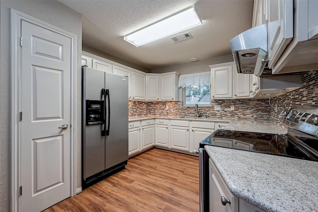 kitchen featuring visible vents, appliances with stainless steel finishes, a textured ceiling, light wood-type flooring, and white cabinetry