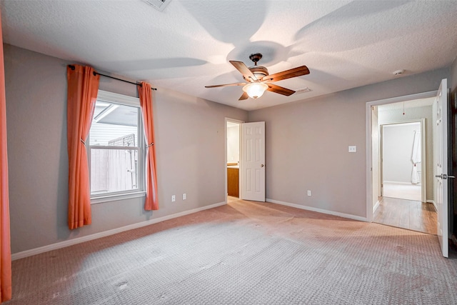 unfurnished bedroom featuring a textured ceiling, light colored carpet, attic access, and baseboards