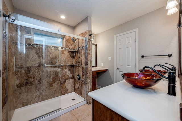 bathroom featuring a textured ceiling, a textured wall, tile patterned flooring, vanity, and a shower stall