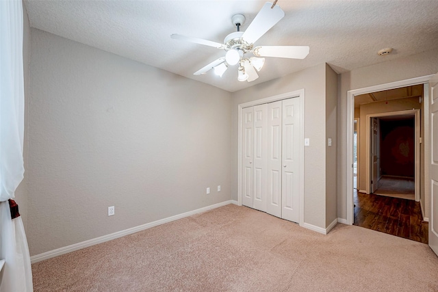 unfurnished bedroom with carpet, a closet, attic access, a textured ceiling, and baseboards