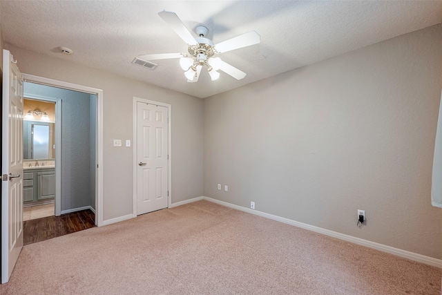 unfurnished bedroom featuring a textured ceiling, dark carpet, visible vents, and baseboards