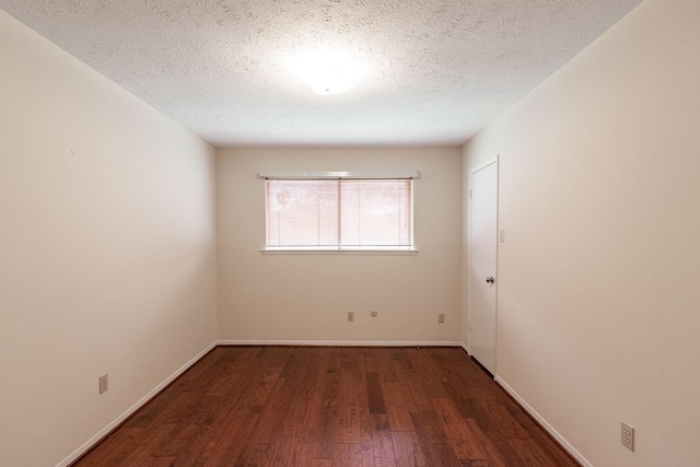 empty room featuring a textured ceiling, baseboards, and dark wood-style flooring