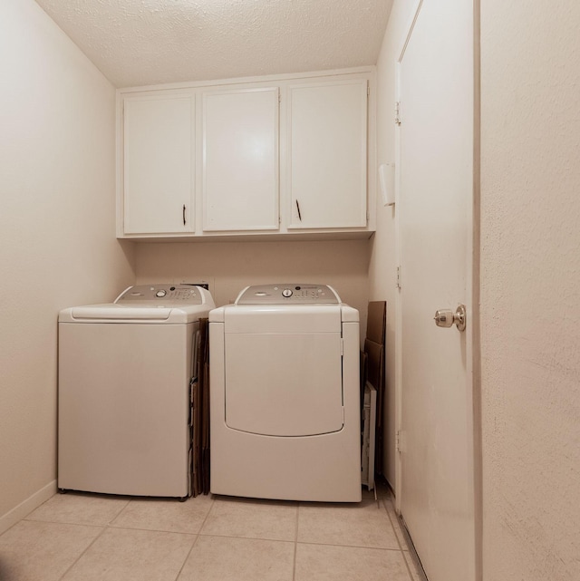 clothes washing area featuring cabinet space, light tile patterned floors, baseboards, a textured ceiling, and separate washer and dryer