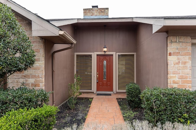 property entrance with stone siding, brick siding, and a chimney