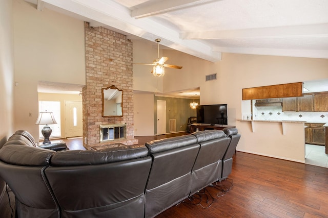 living room with ceiling fan with notable chandelier, dark wood-style flooring, a fireplace, visible vents, and beam ceiling