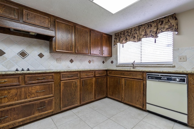 kitchen with light stone counters, backsplash, white dishwasher, a sink, and black electric cooktop