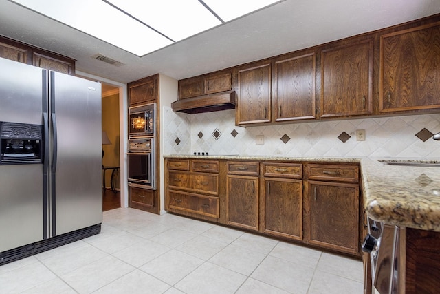 kitchen featuring visible vents, stainless steel fridge with ice dispenser, oven, under cabinet range hood, and black microwave