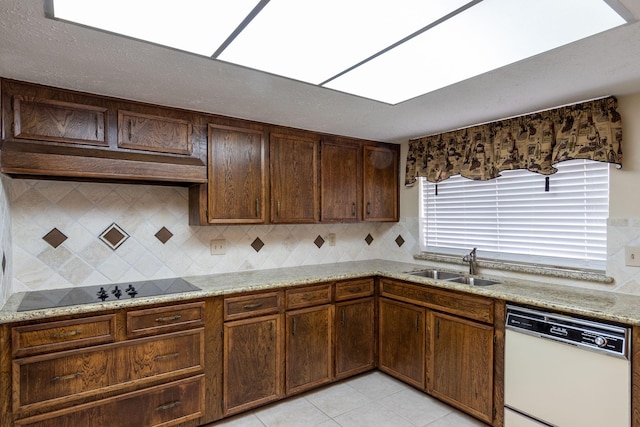 kitchen with a sink, black electric stovetop, light stone counters, and dishwasher