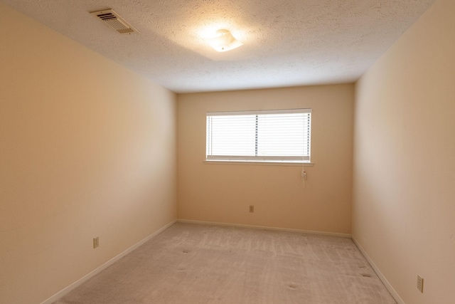 unfurnished room with visible vents, light carpet, baseboards, and a textured ceiling