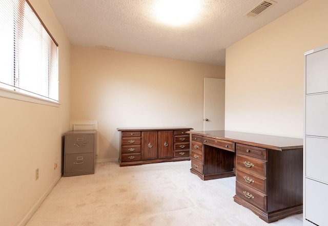 unfurnished office featuring baseboards, visible vents, light carpet, and a textured ceiling