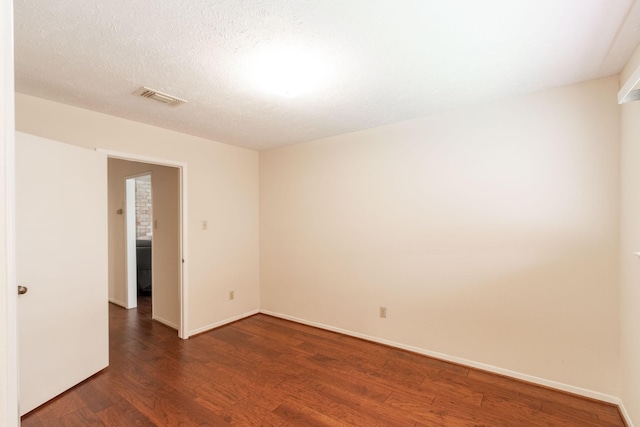 unfurnished room featuring baseboards, a textured ceiling, visible vents, and dark wood-style flooring