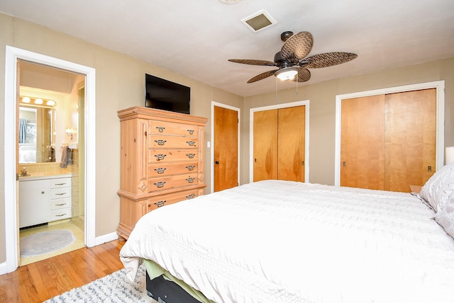 bedroom with multiple closets, a ceiling fan, connected bathroom, light wood-style floors, and baseboards