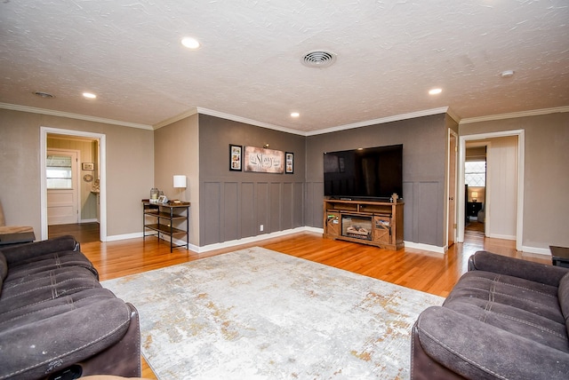 living room featuring hardwood / wood-style flooring, a textured ceiling, and ornamental molding