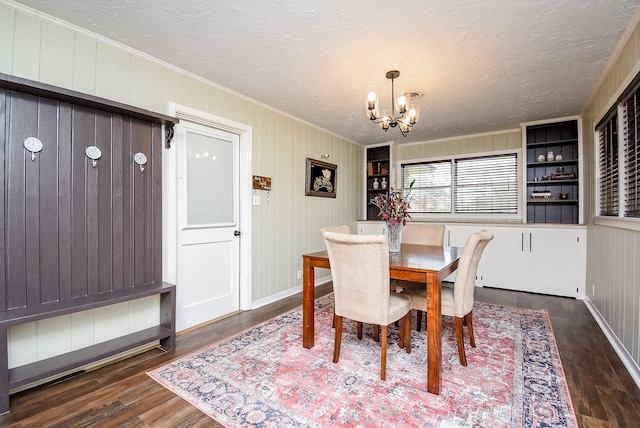 dining area with ornamental molding, dark wood-type flooring, a chandelier, and a textured ceiling