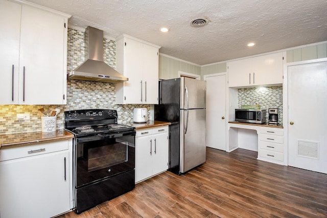 kitchen with built in desk, wall chimney range hood, white cabinets, and stainless steel appliances