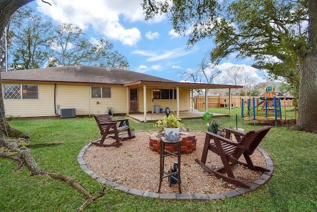 rear view of property featuring central air condition unit, a patio, a playground, and a lawn