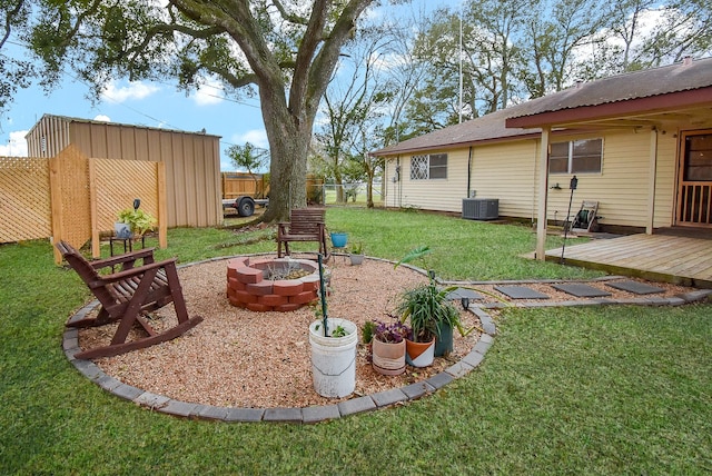 view of yard featuring central air condition unit, a deck, and an outdoor fire pit