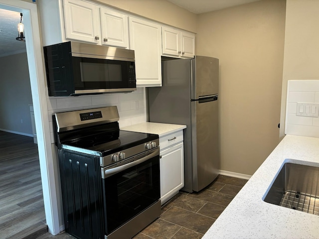 kitchen with decorative backsplash, stainless steel appliances, white cabinets, and light stone counters