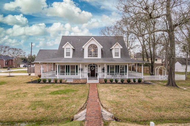 view of front facade with covered porch, a front yard, and fence