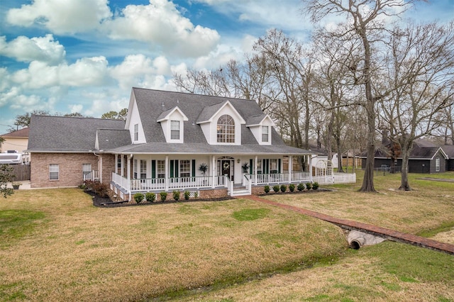 view of front of property with roof with shingles, a porch, a front lawn, and brick siding