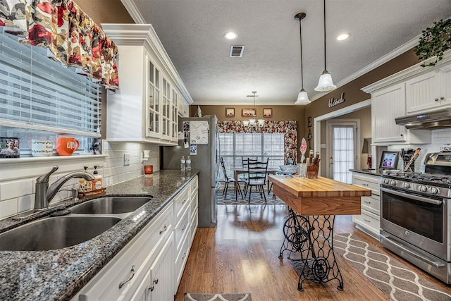 kitchen featuring glass insert cabinets, appliances with stainless steel finishes, under cabinet range hood, white cabinetry, and a sink