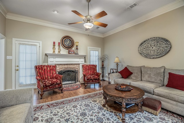 living room with crown molding, visible vents, ceiling fan, and wood finished floors