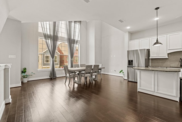 dining room featuring sink, dark wood-type flooring, and a high ceiling