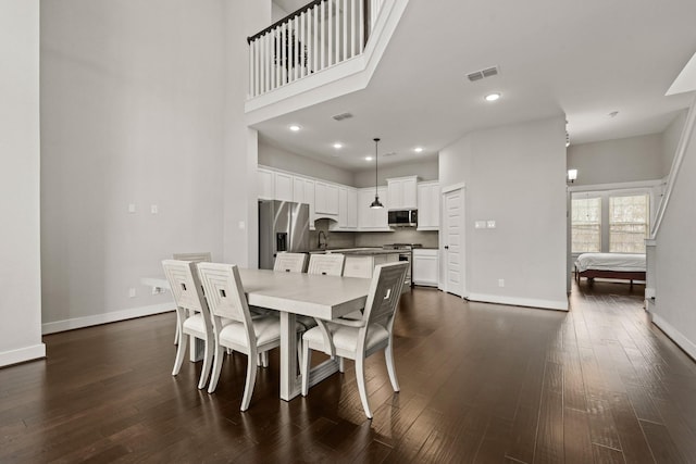 dining area featuring sink, a high ceiling, and dark hardwood / wood-style floors