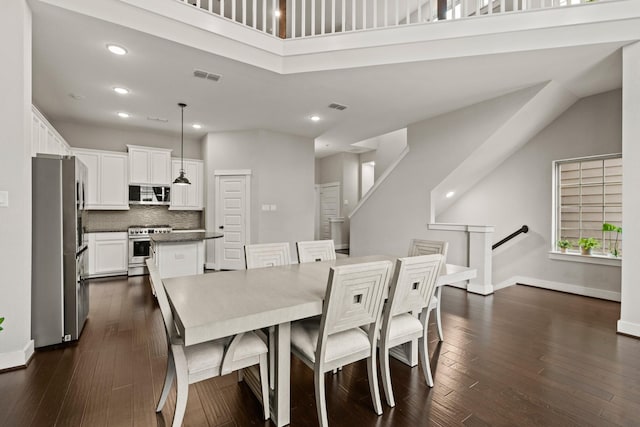 dining space with a high ceiling and dark hardwood / wood-style floors