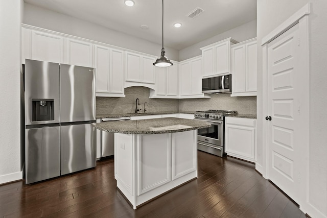 kitchen featuring dark stone countertops, sink, pendant lighting, stainless steel appliances, and white cabinets