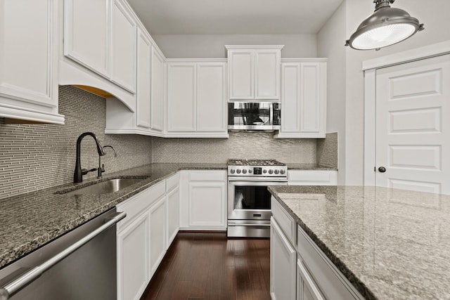 kitchen featuring white cabinets, appliances with stainless steel finishes, sink, and dark stone counters