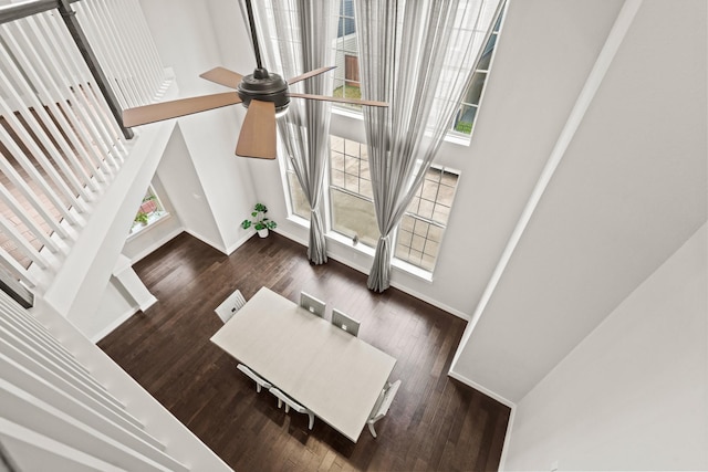 living room with plenty of natural light, dark wood-type flooring, and a towering ceiling