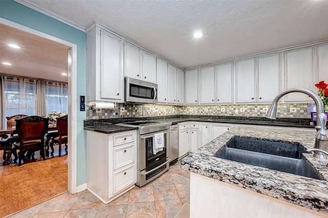 kitchen featuring dark stone counters, backsplash, appliances with stainless steel finishes, and a sink