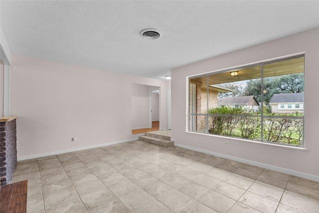 unfurnished living room with a wealth of natural light, light tile patterned floors, and a textured ceiling