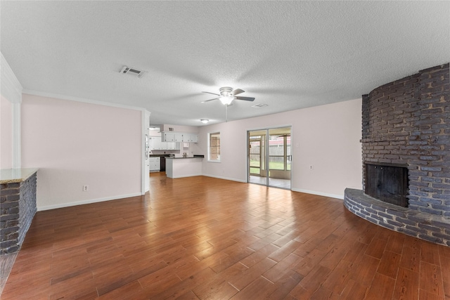 unfurnished living room featuring ceiling fan, dark hardwood / wood-style flooring, a textured ceiling, and a fireplace