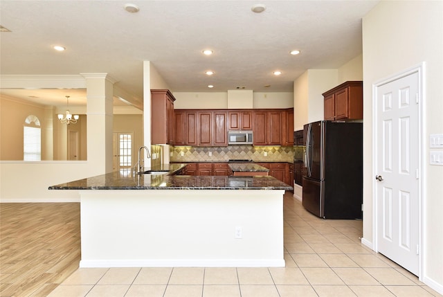 kitchen with refrigerator, sink, dark stone counters, and kitchen peninsula