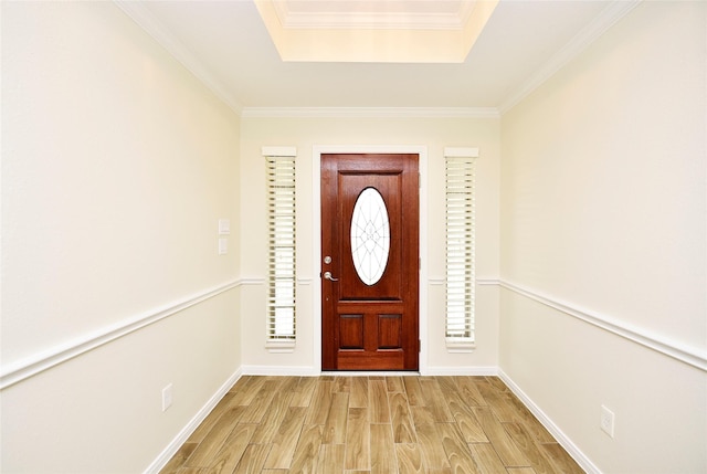 foyer entrance with crown molding, light hardwood / wood-style flooring, and a tray ceiling