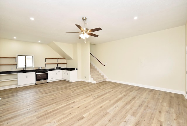 interior space with light hardwood / wood-style flooring, sink, gas range, and white cabinets