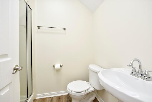 bathroom featuring toilet, a shower with shower door, vaulted ceiling, hardwood / wood-style floors, and sink