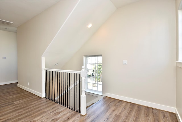 hall with lofted ceiling and light hardwood / wood-style floors