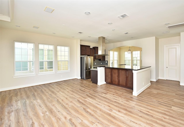 kitchen featuring light hardwood / wood-style flooring, stainless steel refrigerator, backsplash, dark brown cabinets, and island range hood