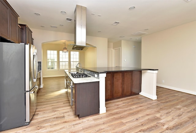 kitchen with light wood-type flooring, a kitchen island with sink, dark brown cabinetry, appliances with stainless steel finishes, and island exhaust hood