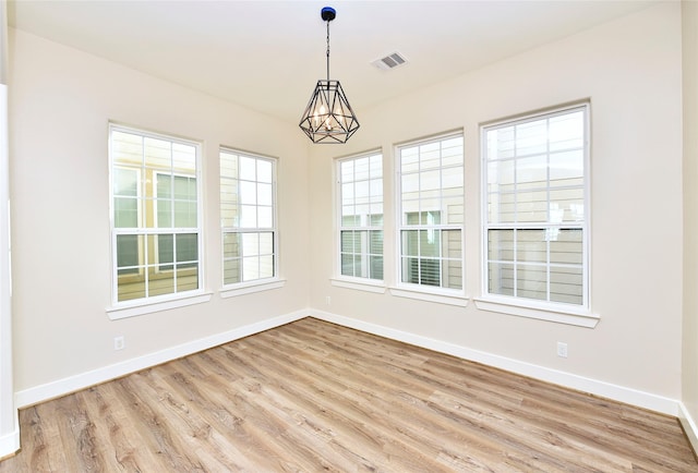 unfurnished room with light hardwood / wood-style floors and an inviting chandelier