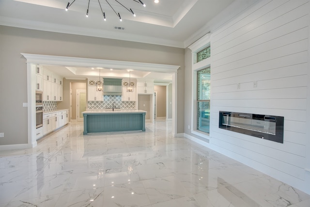 kitchen featuring a tray ceiling, pendant lighting, stainless steel appliances, and white cabinets