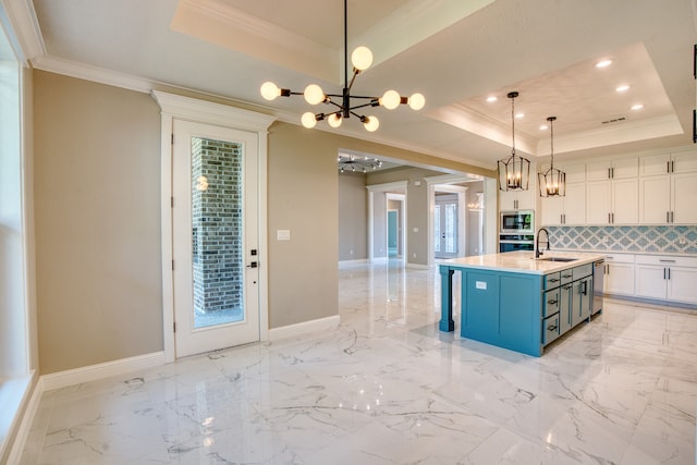 kitchen featuring a center island with sink, decorative light fixtures, a raised ceiling, and white cabinets