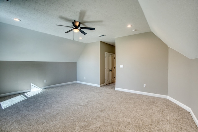 additional living space featuring light colored carpet, lofted ceiling, ceiling fan, and a textured ceiling