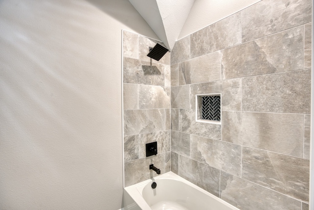 bathroom featuring lofted ceiling and tiled shower / bath combo