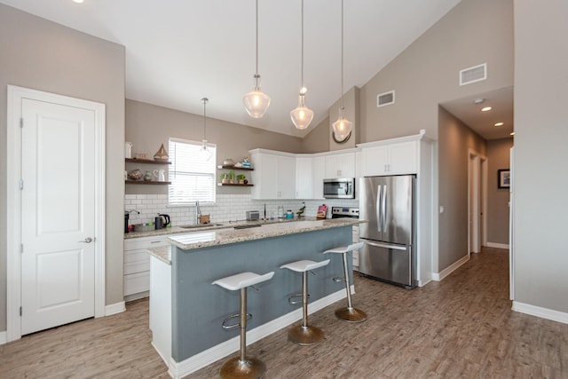 kitchen with sink, a kitchen island, appliances with stainless steel finishes, and white cabinets